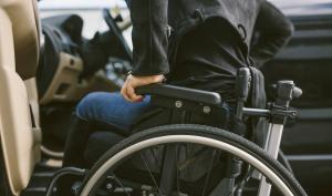 Un homme dans un fauteuil roulant s'apprête à s'installer au volant d'une voiture