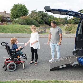 Photo d'un enfant en fauteuil s'apprêtant à entrer dans un véhicule.