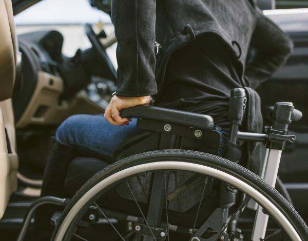 Un homme dans un fauteuil roulant s'apprête à s'installer au volant d'une voiture